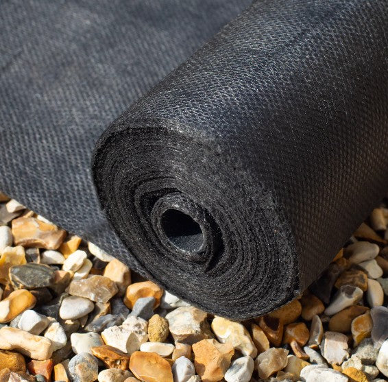 Roll of black landscape fabric on a bed of small stones